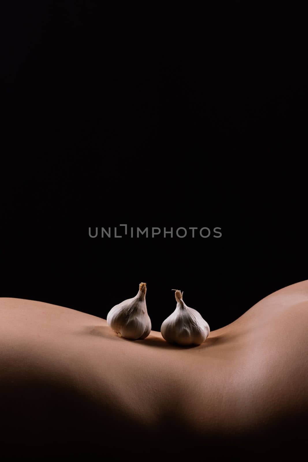 Close up of woman back with laying garlic, low key by Zelenin