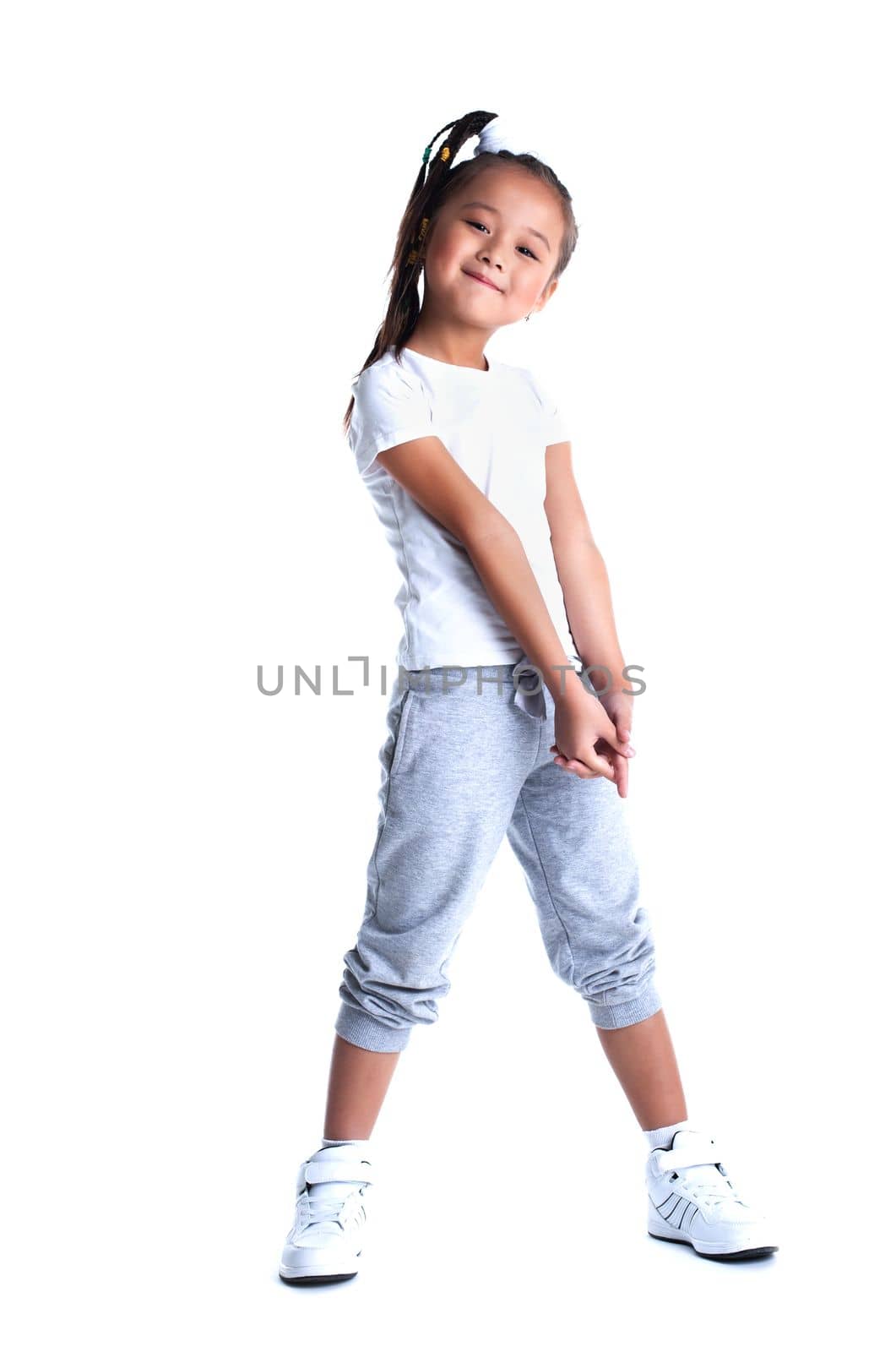 Full length portrait of asian little girl in sportswear. Isolated on white