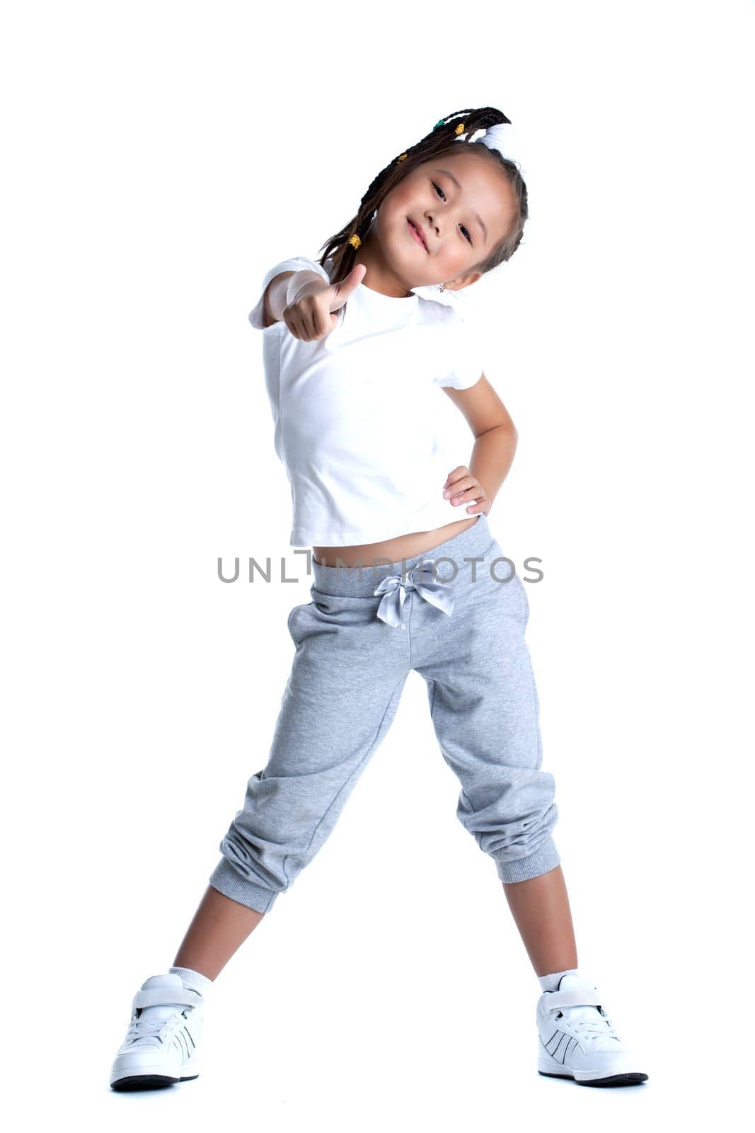 portrait of pretty asian little girl in sportswear thumbs up. Isolated on white