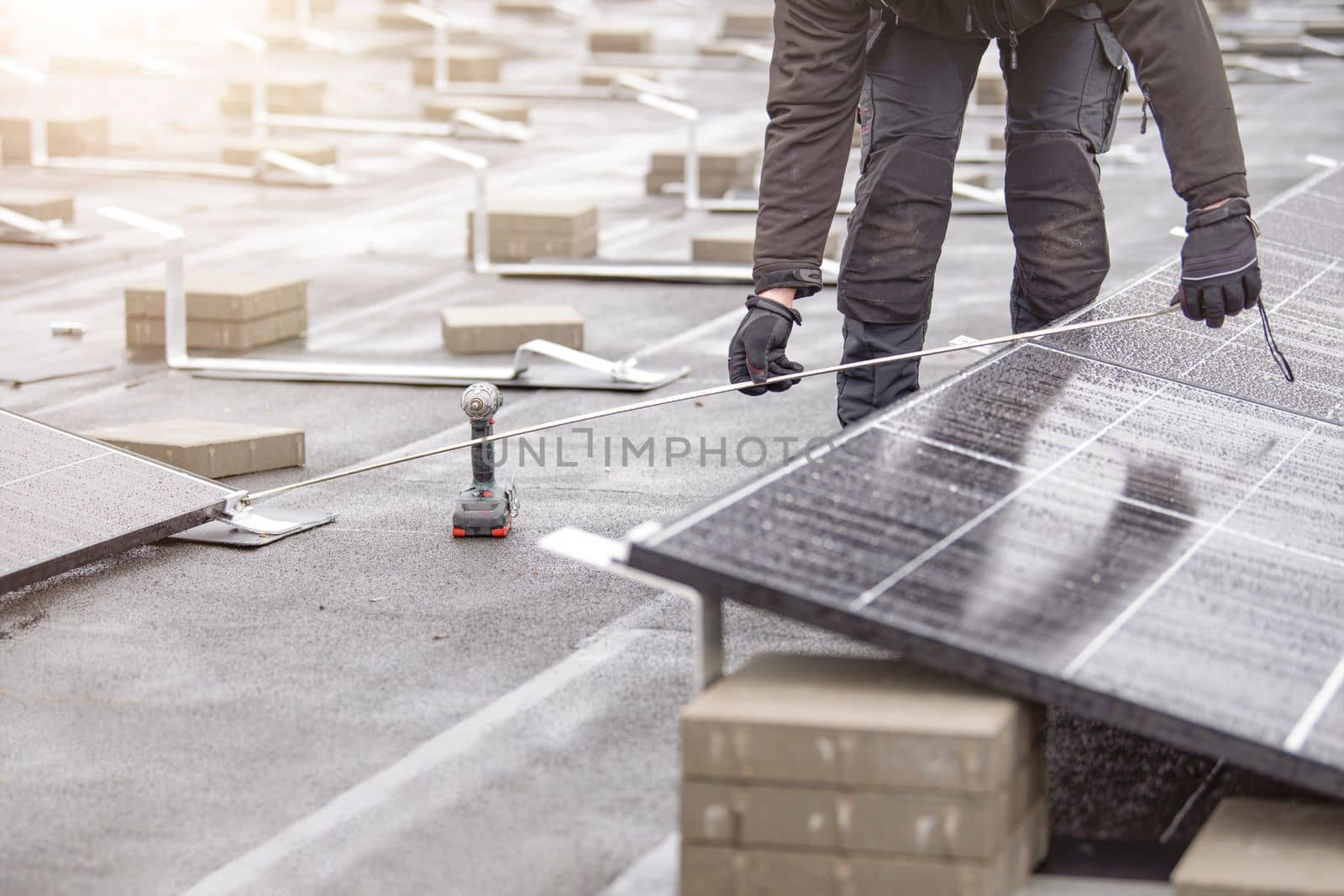 The process of installing solar panels. The installer measures the distance between solar panel modules. Green and renewable energy concept.