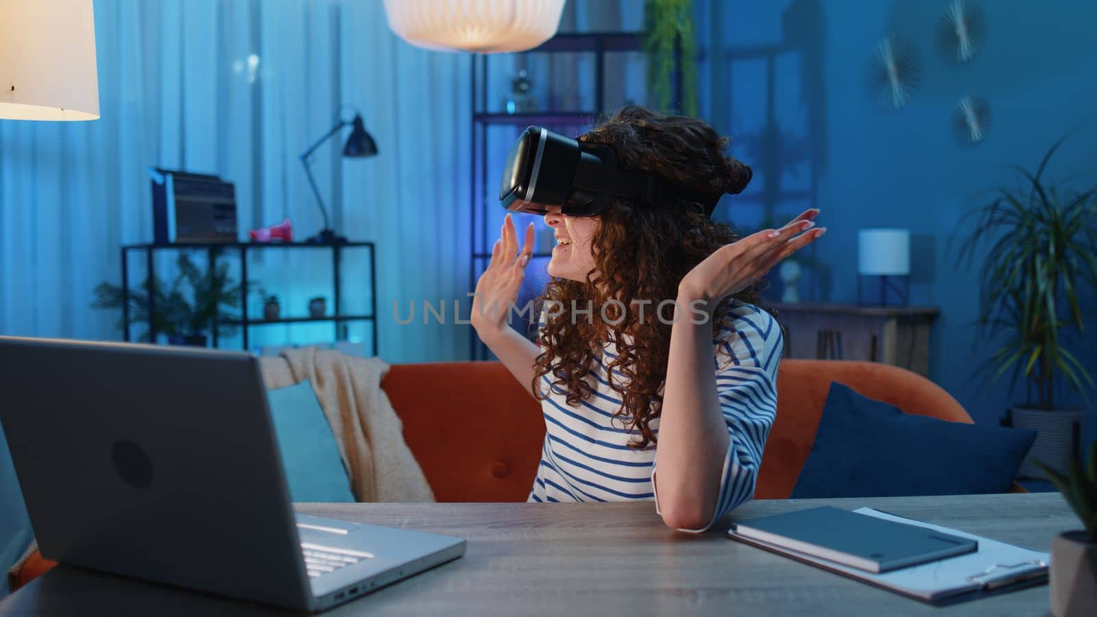 Woman using virtual reality futuristic technology VR app headset helmet play simulation 3D 360 video game watching film movie at home apartment. Girl in goggles sitting on sofa. Transition zoom effect