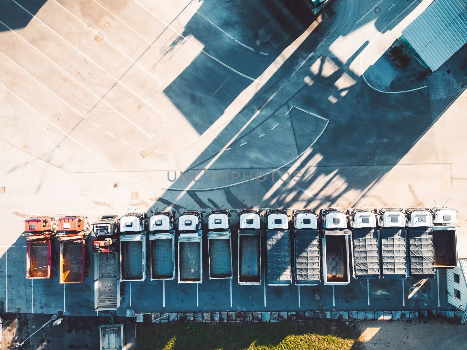 Top down view of construction trucks parked in a line at the road repair base by VisualProductions