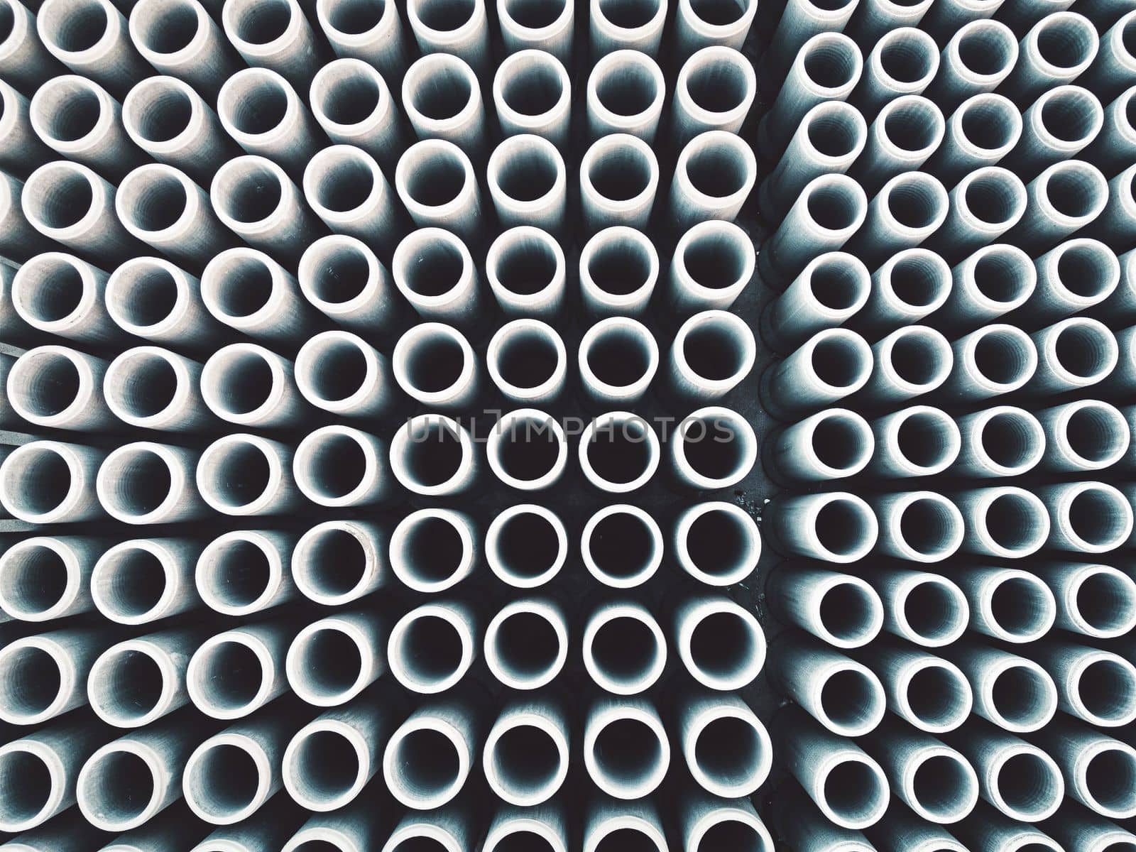 Top down view of round concrete pipes or pillars stacked in rows at the construction firm base by VisualProductions