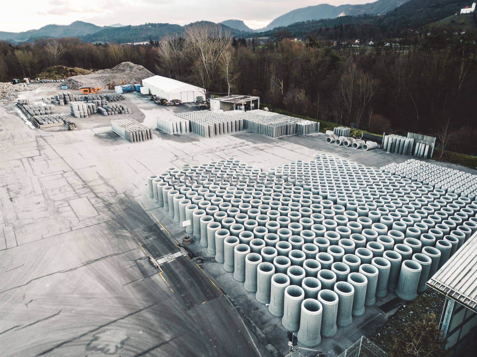 Aerial view at huge concrete pipes neatly stacked in rows at construction company base by VisualProductions