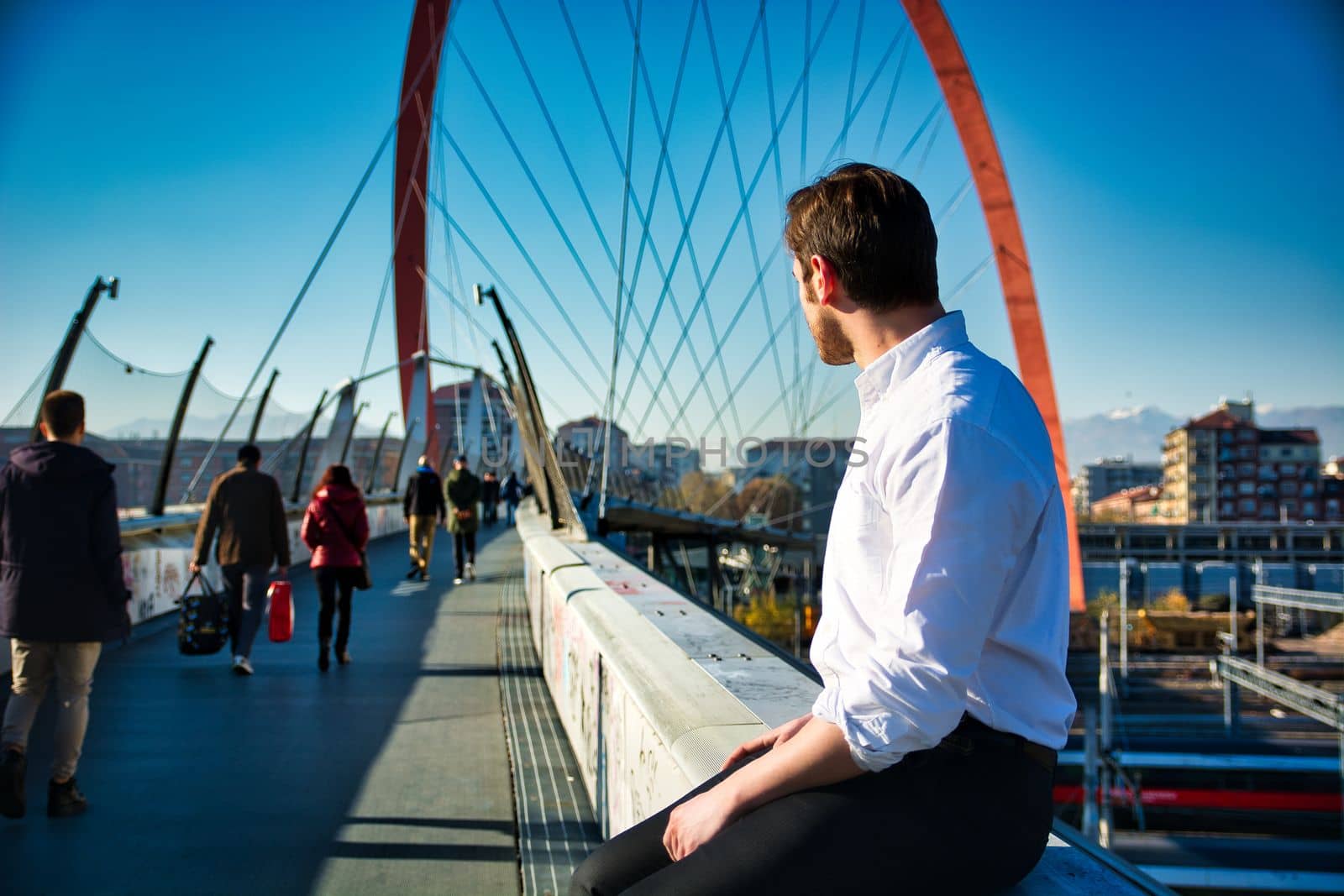 One handsome elegant young man in urban setting in city, sitting, looking away, seen from the back