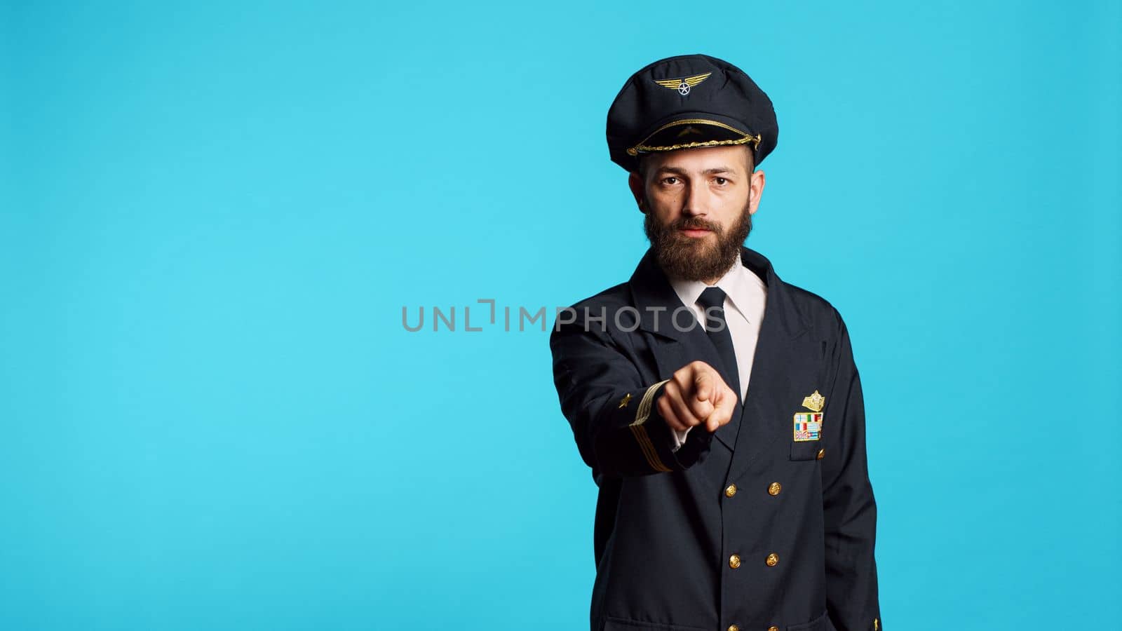 Airplane pilot in uniform pointing at camera by DCStudio