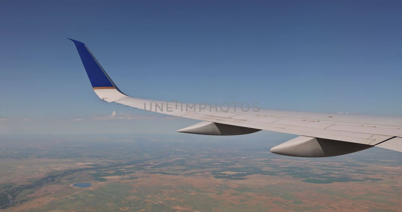 In background you can see an airplane wing aircraft flying above fluffy cloudy sky as seen earth through window