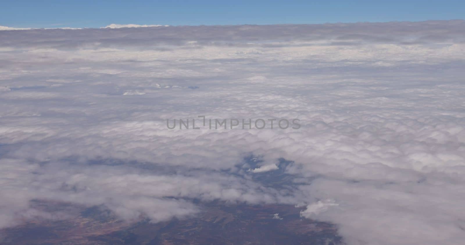 From the window of the airplane, you can see white clouds in a beautiful blue sky over a beautiful landscape by ungvar