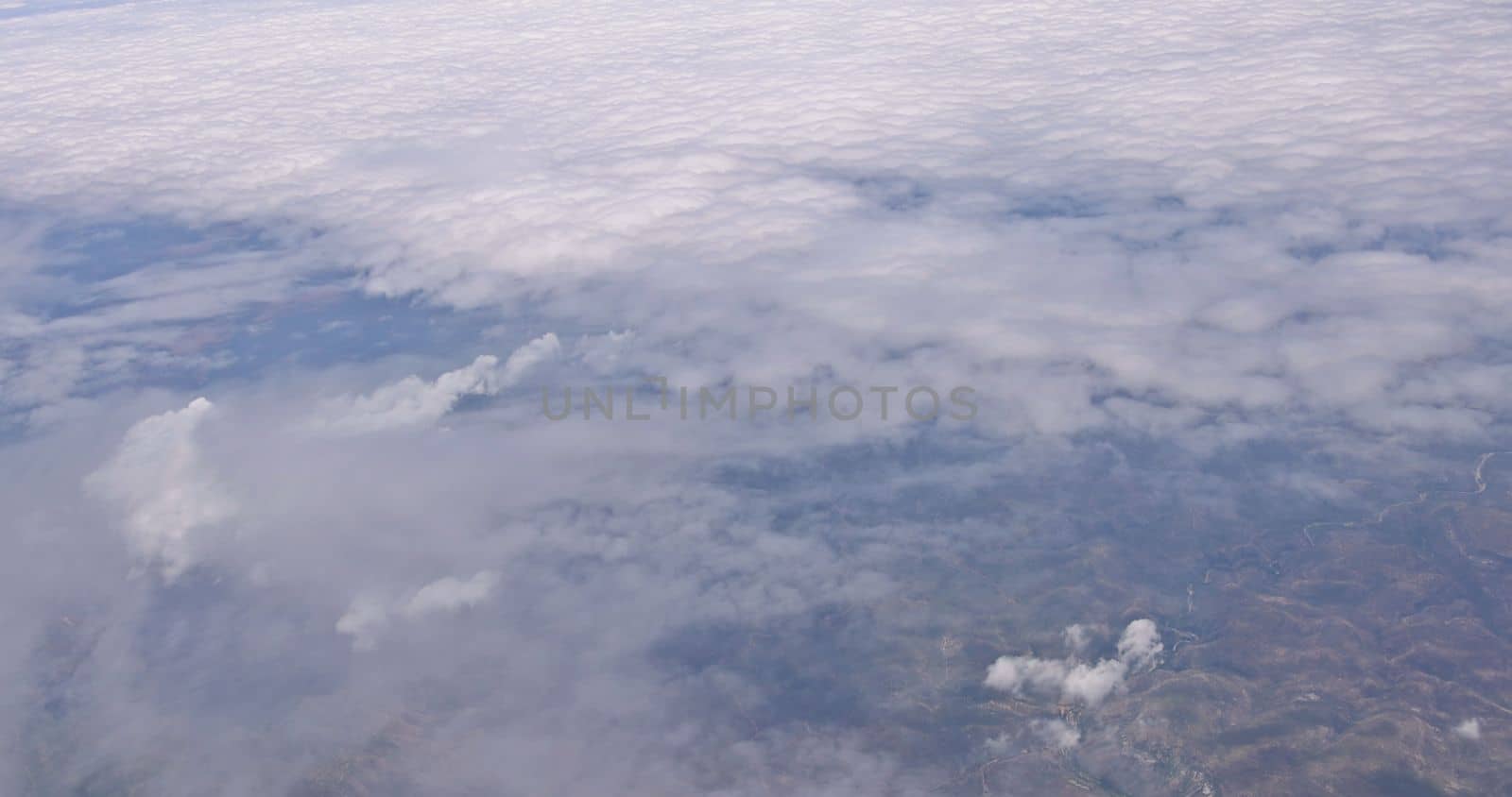 It is beautiful natural landscape view of land from an airplane window with white clouds against blue skies