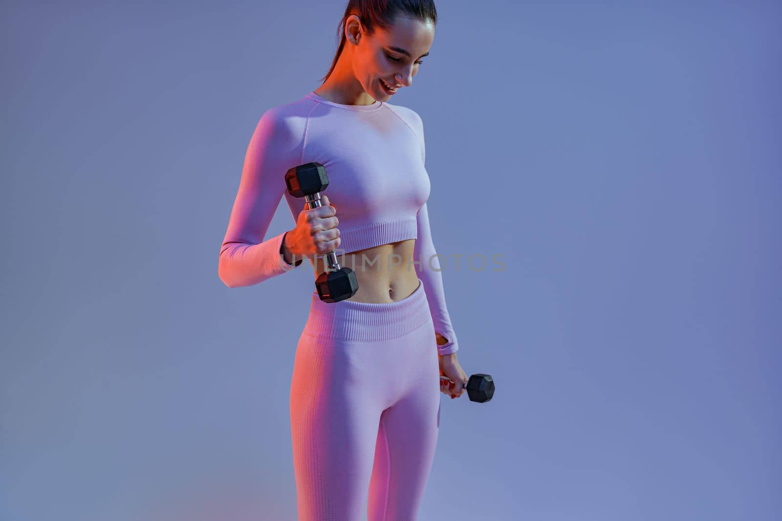 Woman doing exercises with dumbbells on studio background . Sport and healthy lifestyle