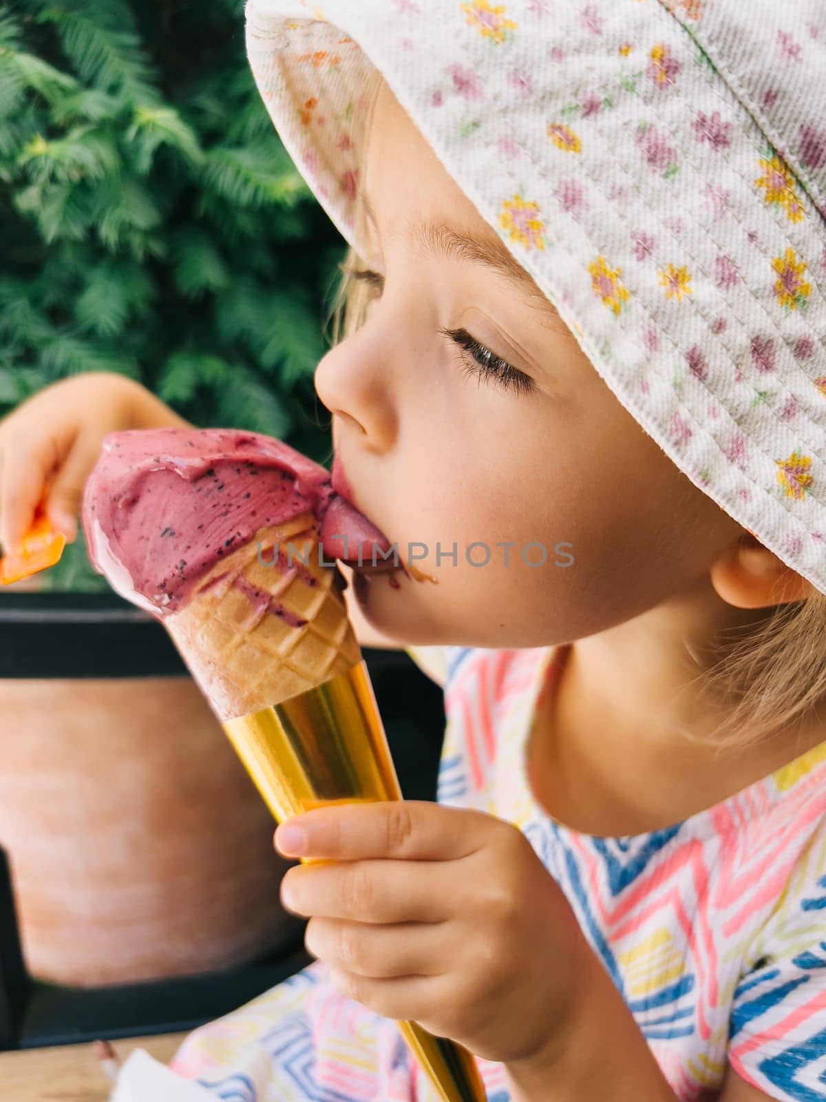 Little girl licks a popsicle in a cone, holding it in her hand. High quality photo