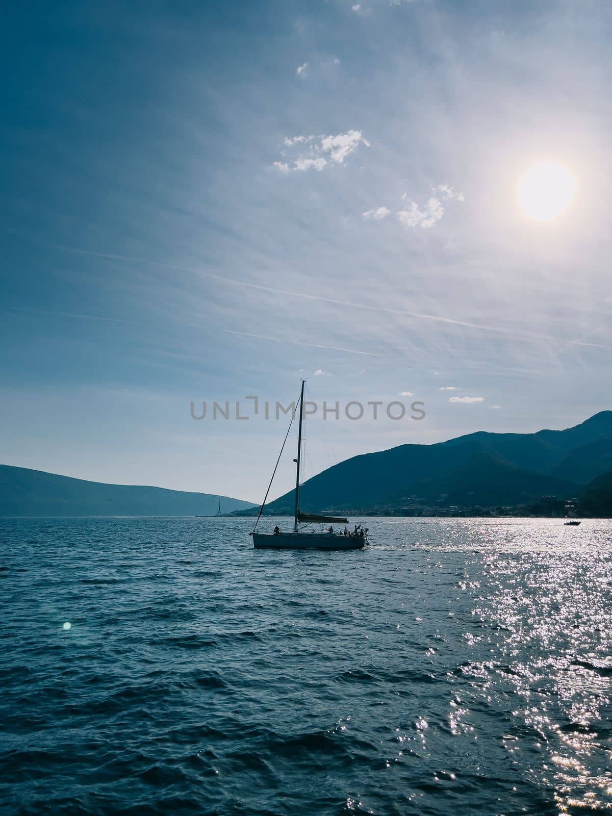 Sailing yacht sails on the sea under bright sunbeams against the backdrop of mountains. High quality photo