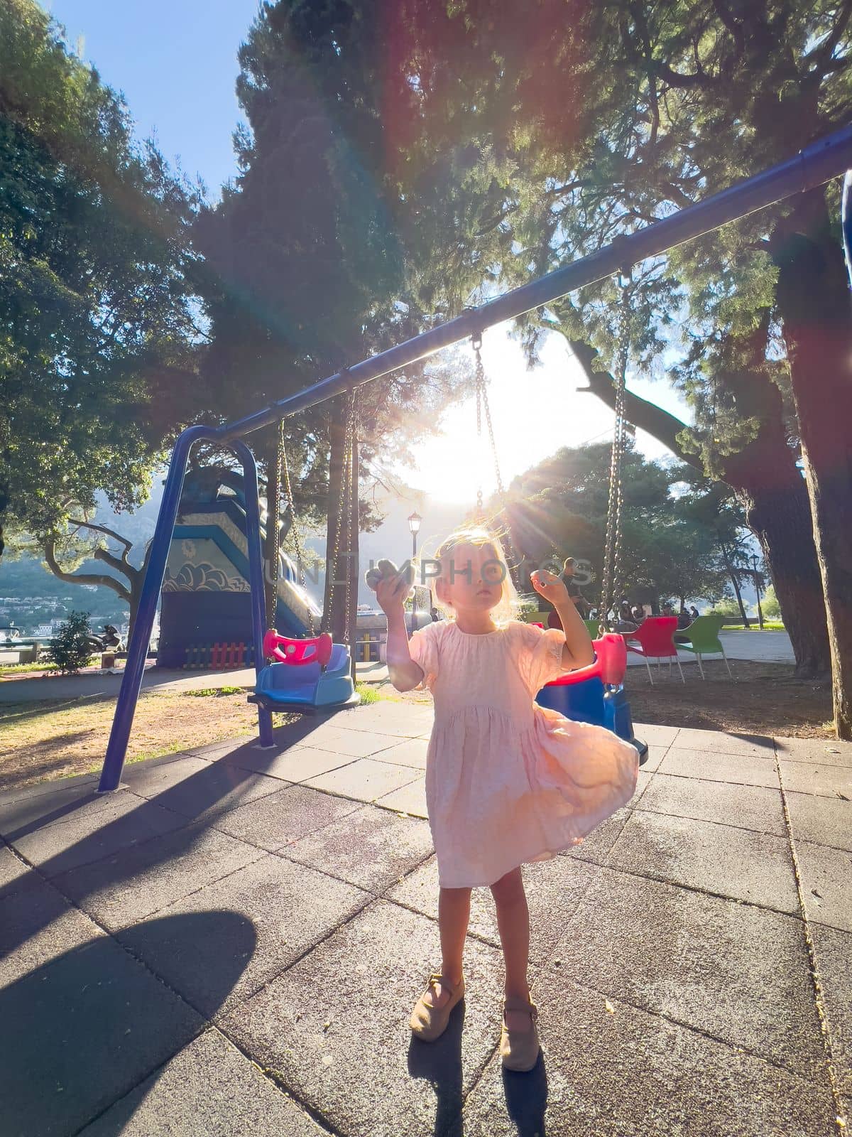 Little girl stands on the playground near the chain swing by Nadtochiy