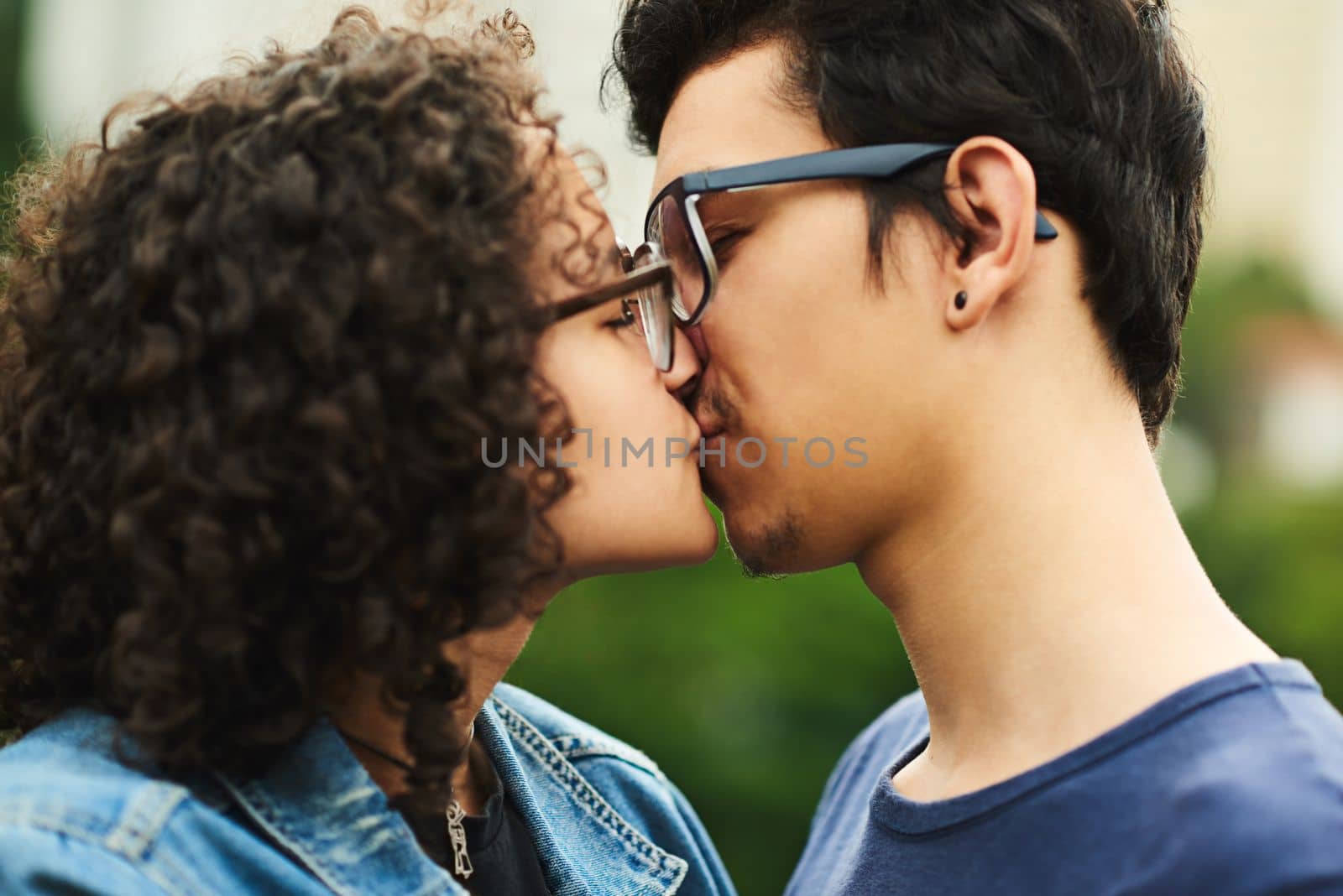 Our first kiss. a teenage couple kissing outdoors. by YuriArcurs