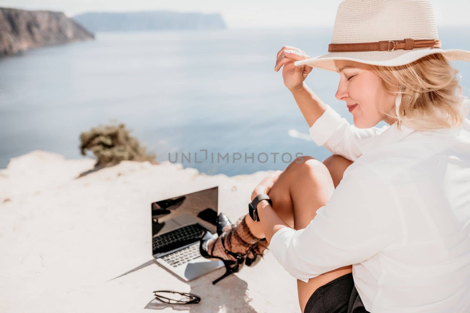 Happy girl doing yoga with laptop working at the beach. beautiful and calm business woman sitting with a laptop in a summer cafe in the lotus position meditating and relaxing. freelance girl remote work beach paradise