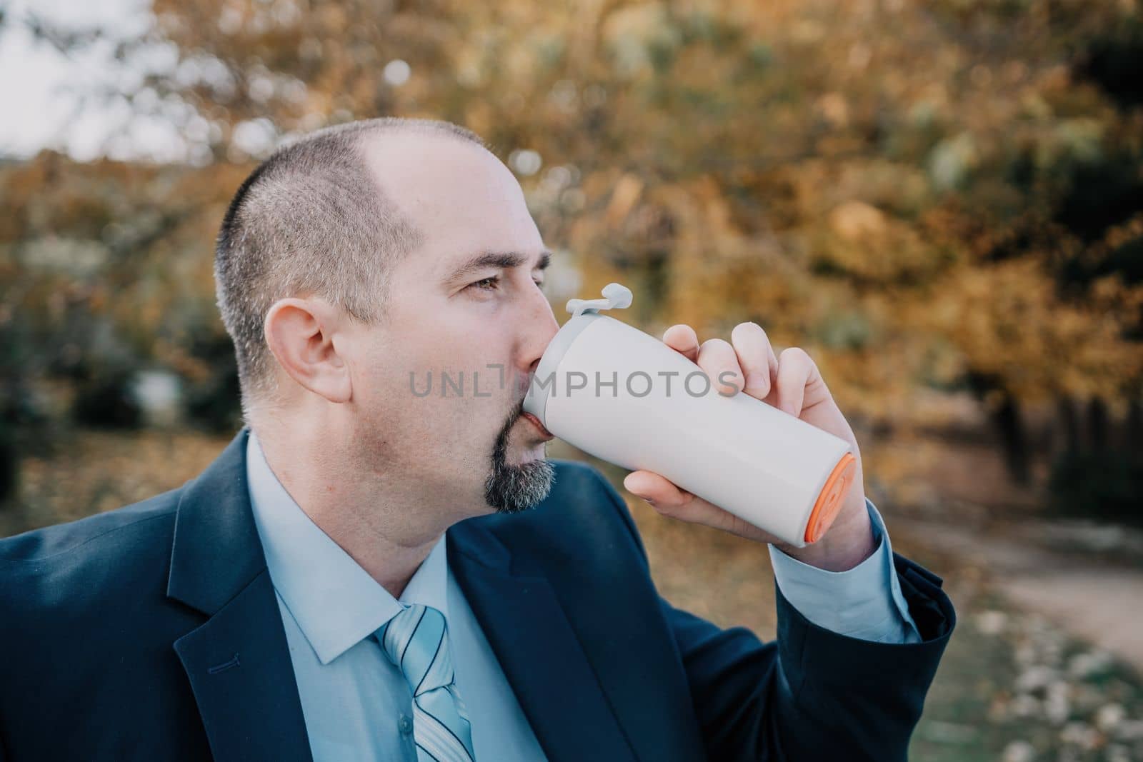 Mature entrepreneur drink coffee in autumn park. Senior executive rest in city park.