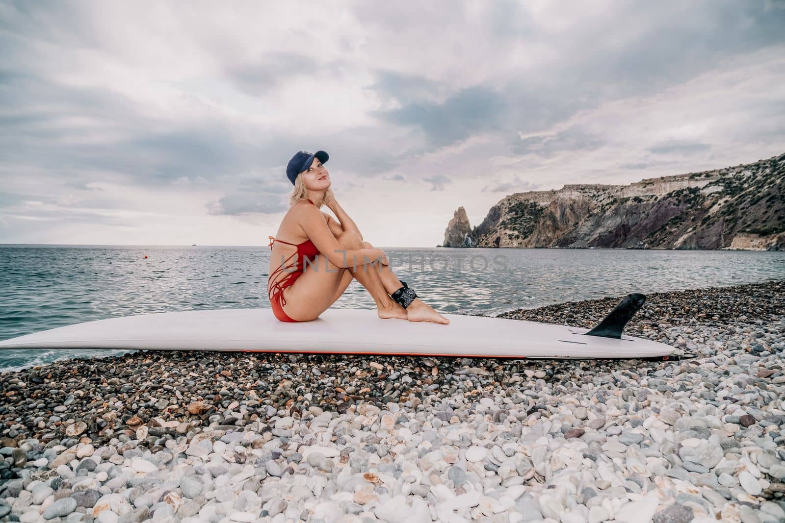 Woman in red bikini on Beach. Happy lady with blond hair in bathing suit chilling and sunbathing by turquoise sea ocean on sunset. Holiday, vacation and recreational concept. Close up by panophotograph