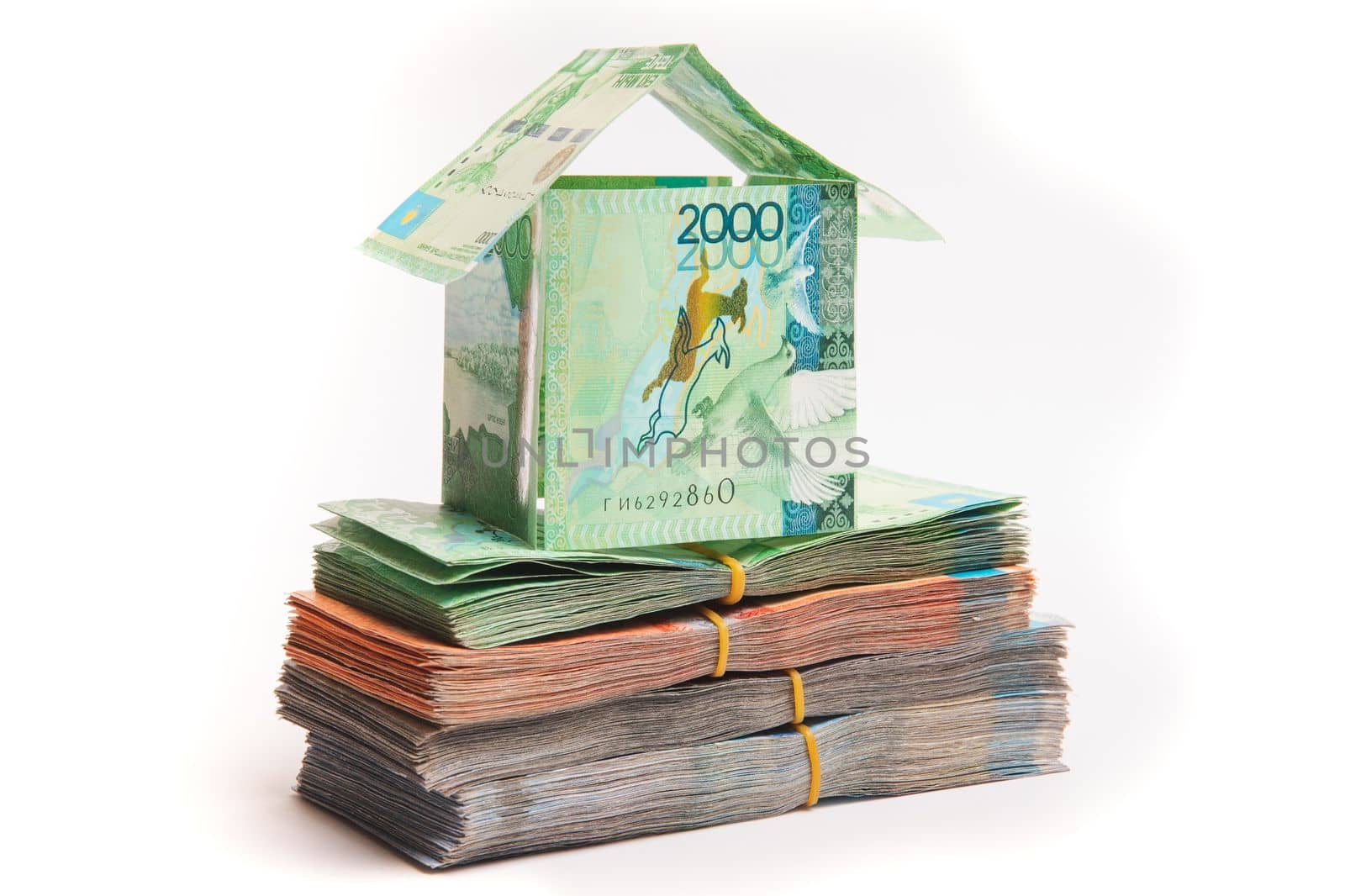 House made of banknotes of Kazakh money stands on packs of tenge. Mortgage concept, real estate appreciation, isolated on white
