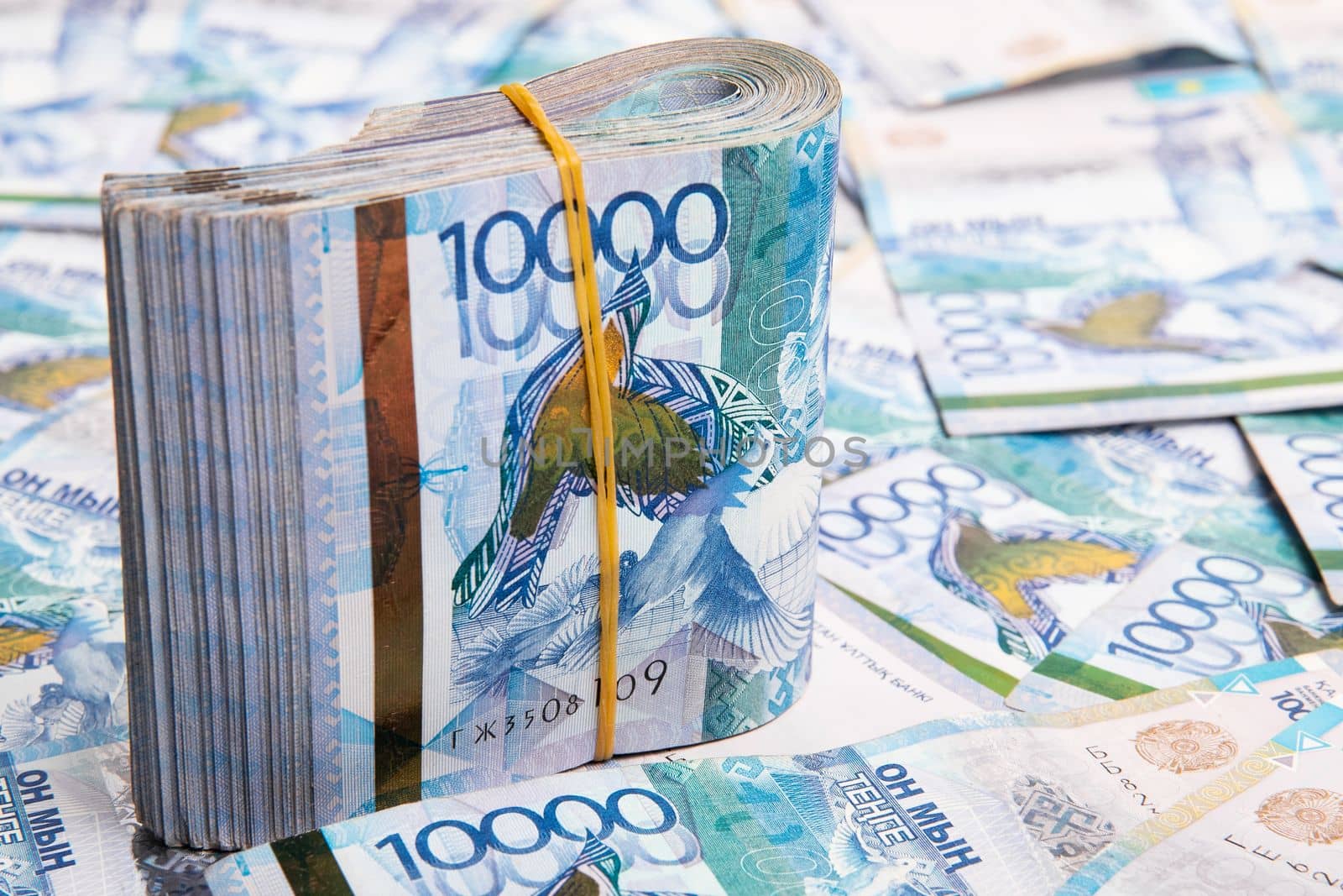 A pack of 10000 banknotes of Kazakhstan tenge, against the background of spread out Kazakhstani money.