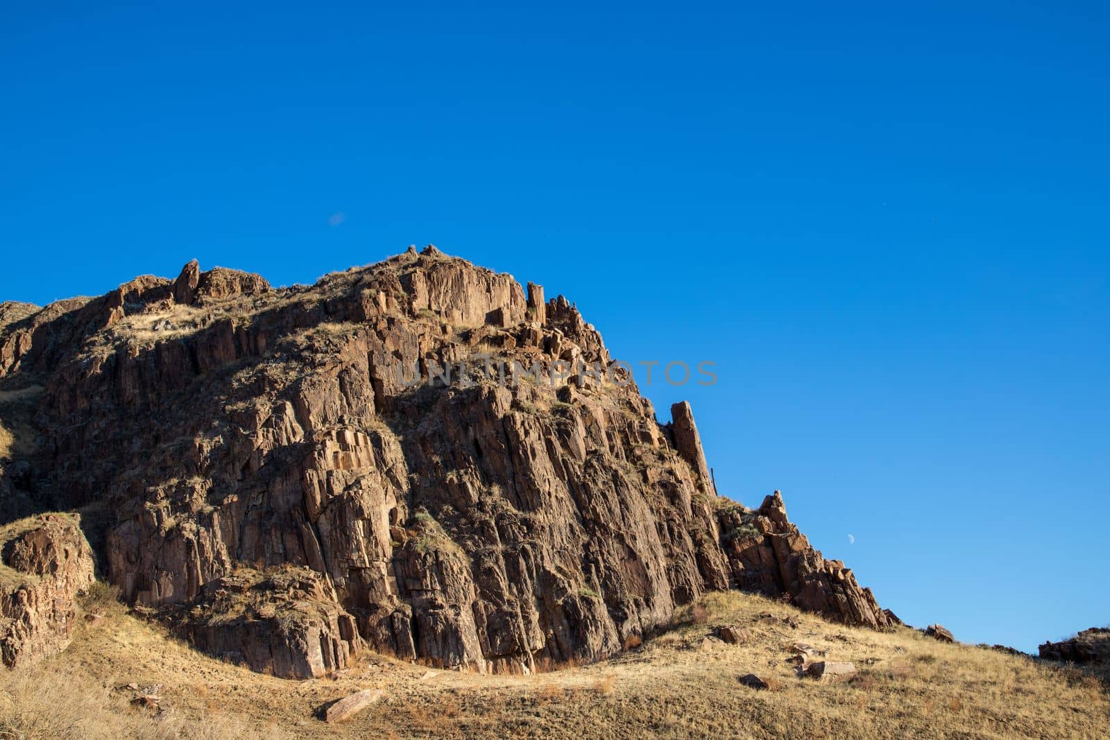 Lonely rock in the Kazakhstan steppe under the blue sky.
