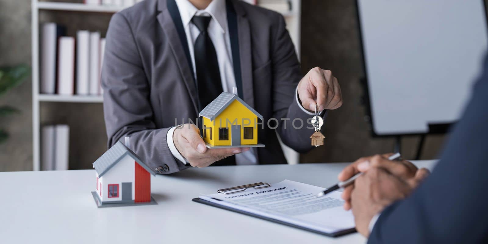 Real estate agent is discussing and explaining the terms of the home purchase contract. Businessman signing a contract agreement, mortgage, rent, lease, home insurance. by wichayada