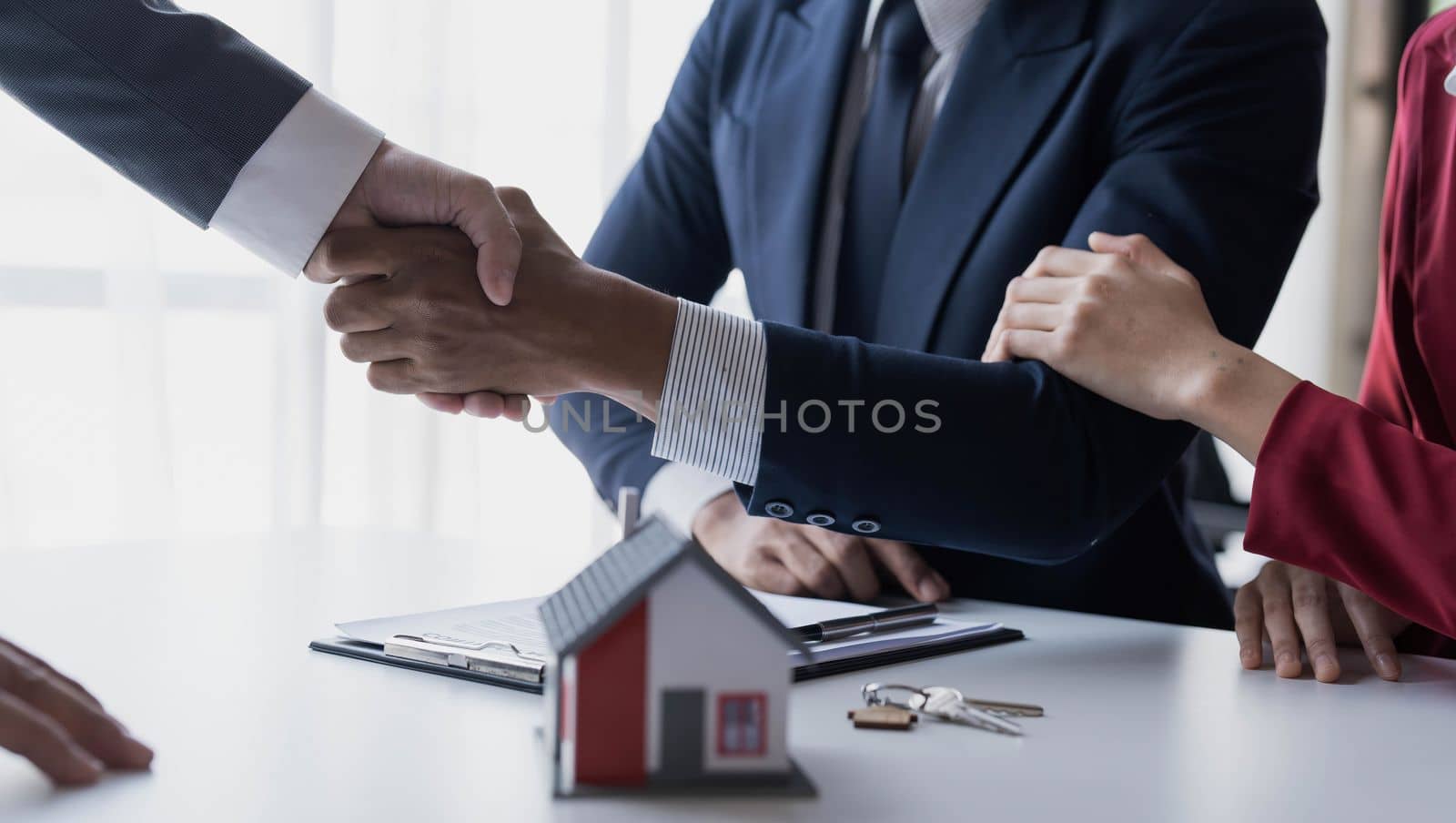 Happy couple first time home owners handshaking realtor insurer landlord bank worker at meeting, asian family customers make real estate deal for rent house purchase or mortgage investment by wichayada