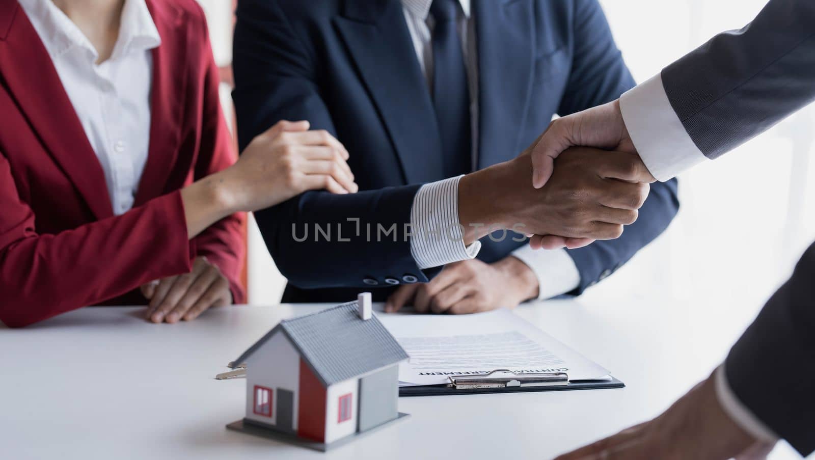 Happy couple first time home owners handshaking realtor insurer landlord bank worker at meeting, asian family customers make real estate deal for rent house purchase or mortgage investment by wichayada