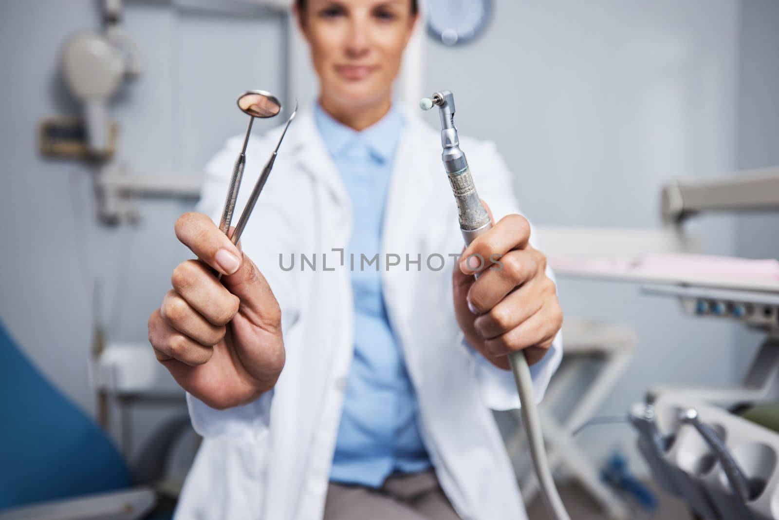 The tools to make your teeth shine. Portrait of a young woman holding teeth cleaning tools in her dentists office. by YuriArcurs