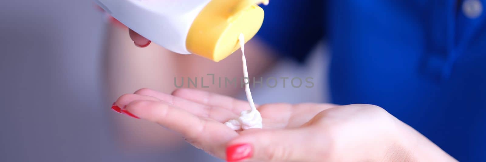 Woman pours body care lotion or sunscreen from bottle into hand. Moisturizing and protecting skin concept