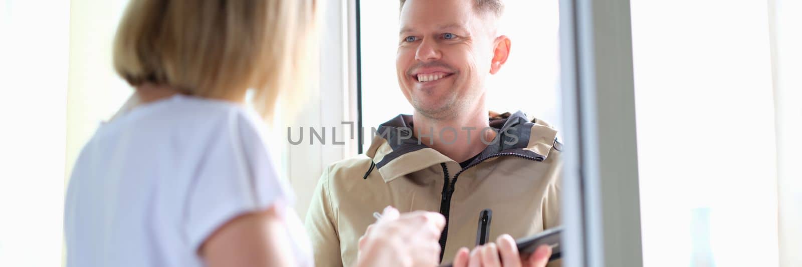 Woman signs on a tablet for parcel from courier at home. Delivery of goods and logistics concept