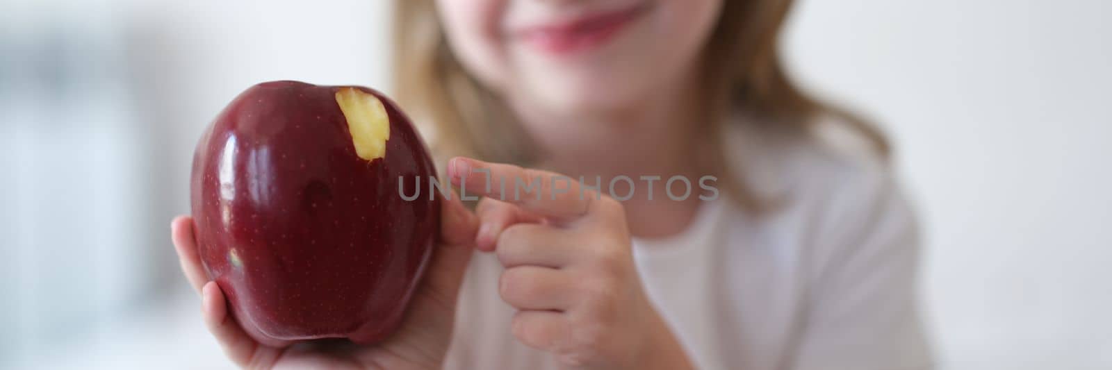 Beautiful little smiling girl eats red ripe apple by kuprevich