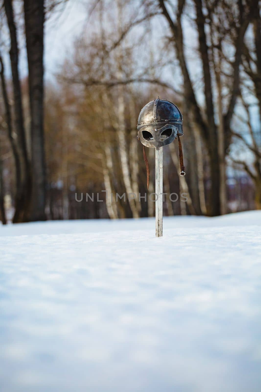 Image of silver sword and helmet fantasy medieval period at the background of winter landscape
