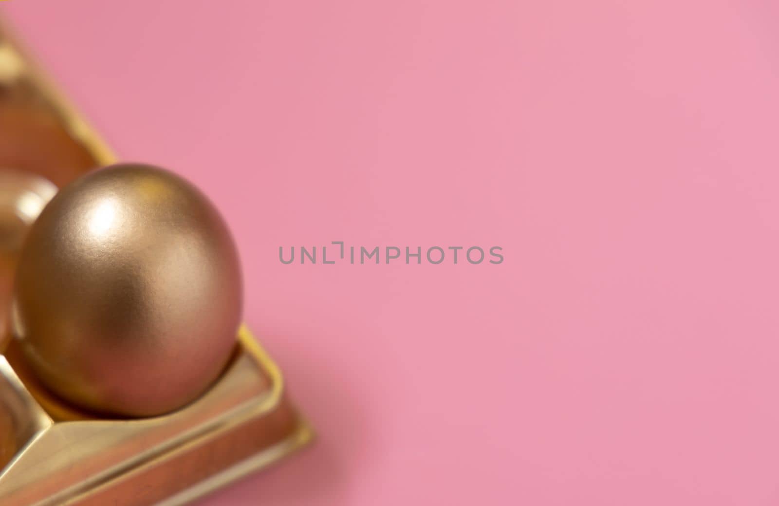 Happy Easter holiday. Golden easter egg in golden box on pastel pink background. by Ri6ka