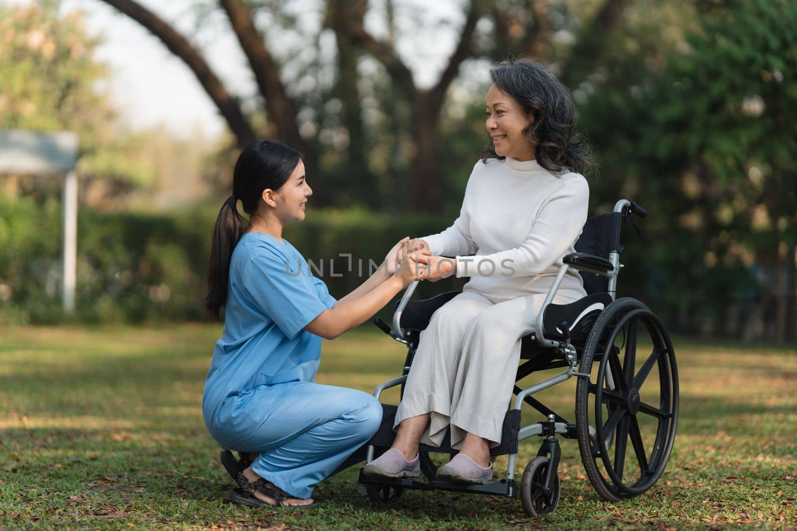 Elderly asian senior woman on wheelchair with nurse. Nursing home hospital garden concept. by itchaznong