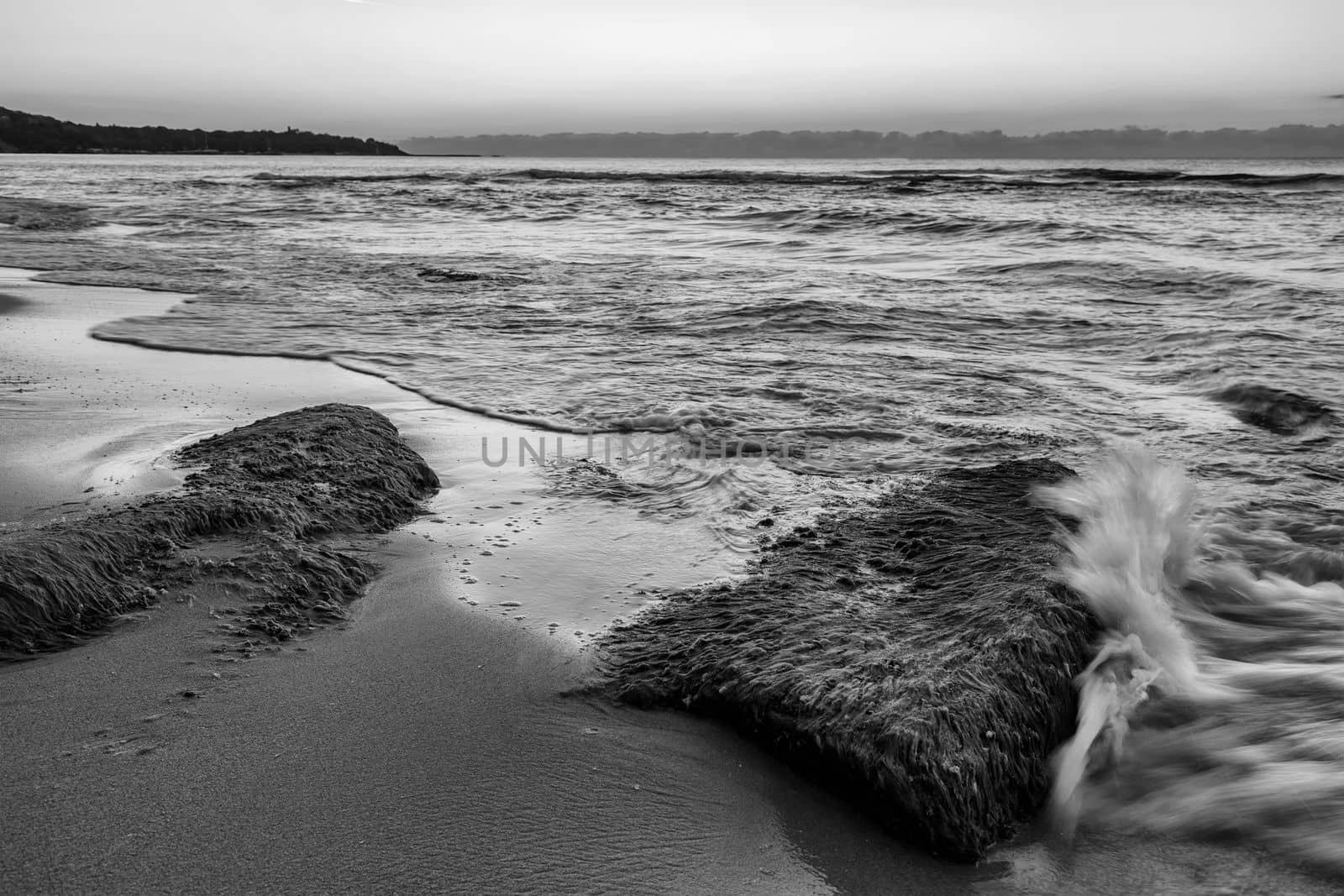 Seascape view with rocks with moss and small wave splash.