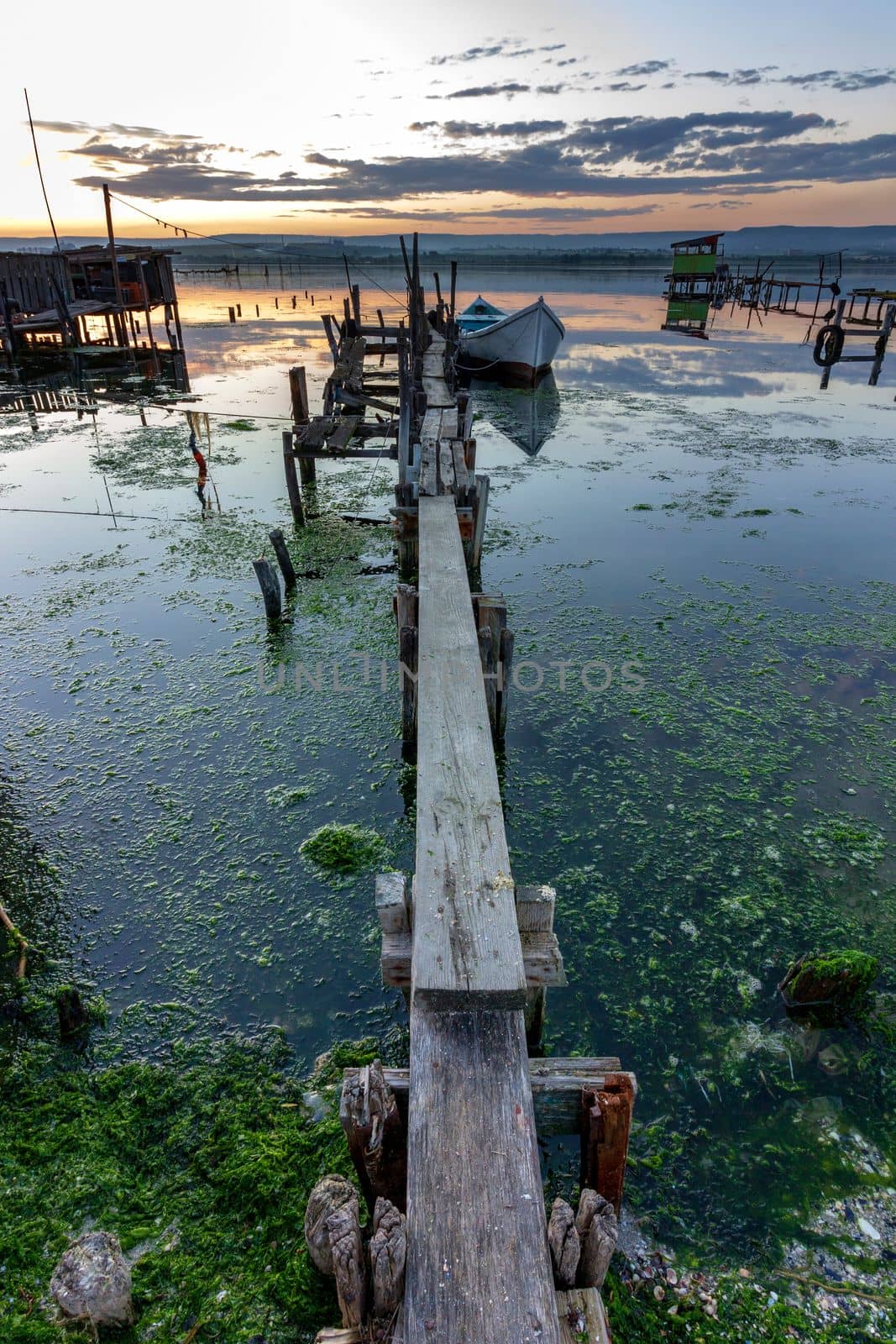 exciting long exposure landscape on a lake with wooden pier and boat .