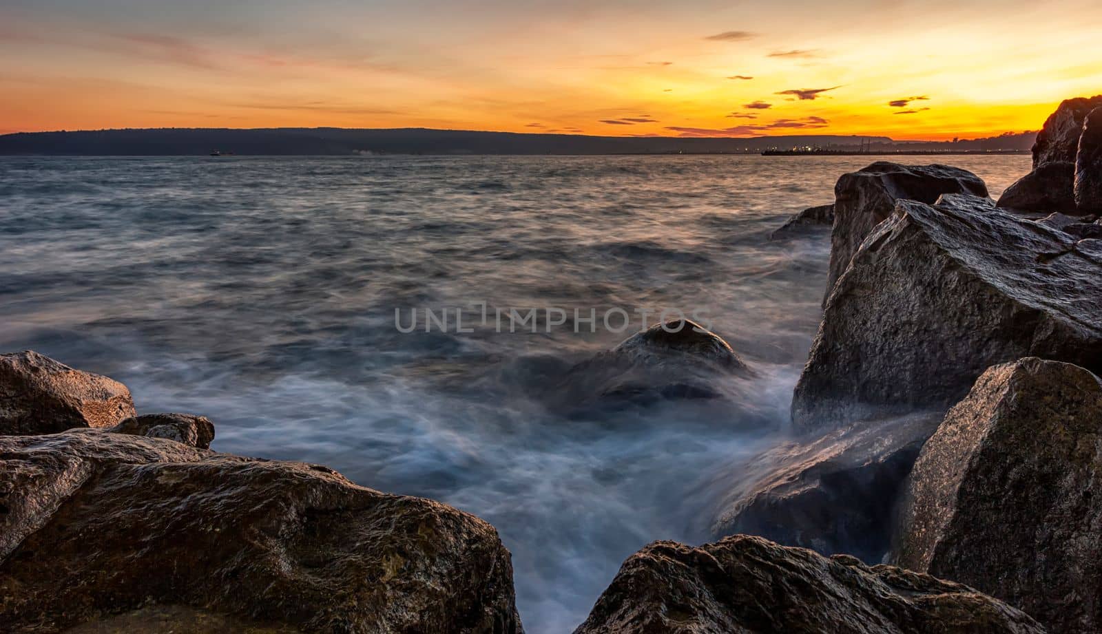 Sunset over the sea. Big rocks in the foreground
