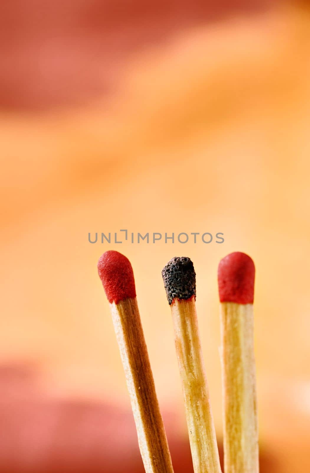 Red matches and one burnt match on colored background