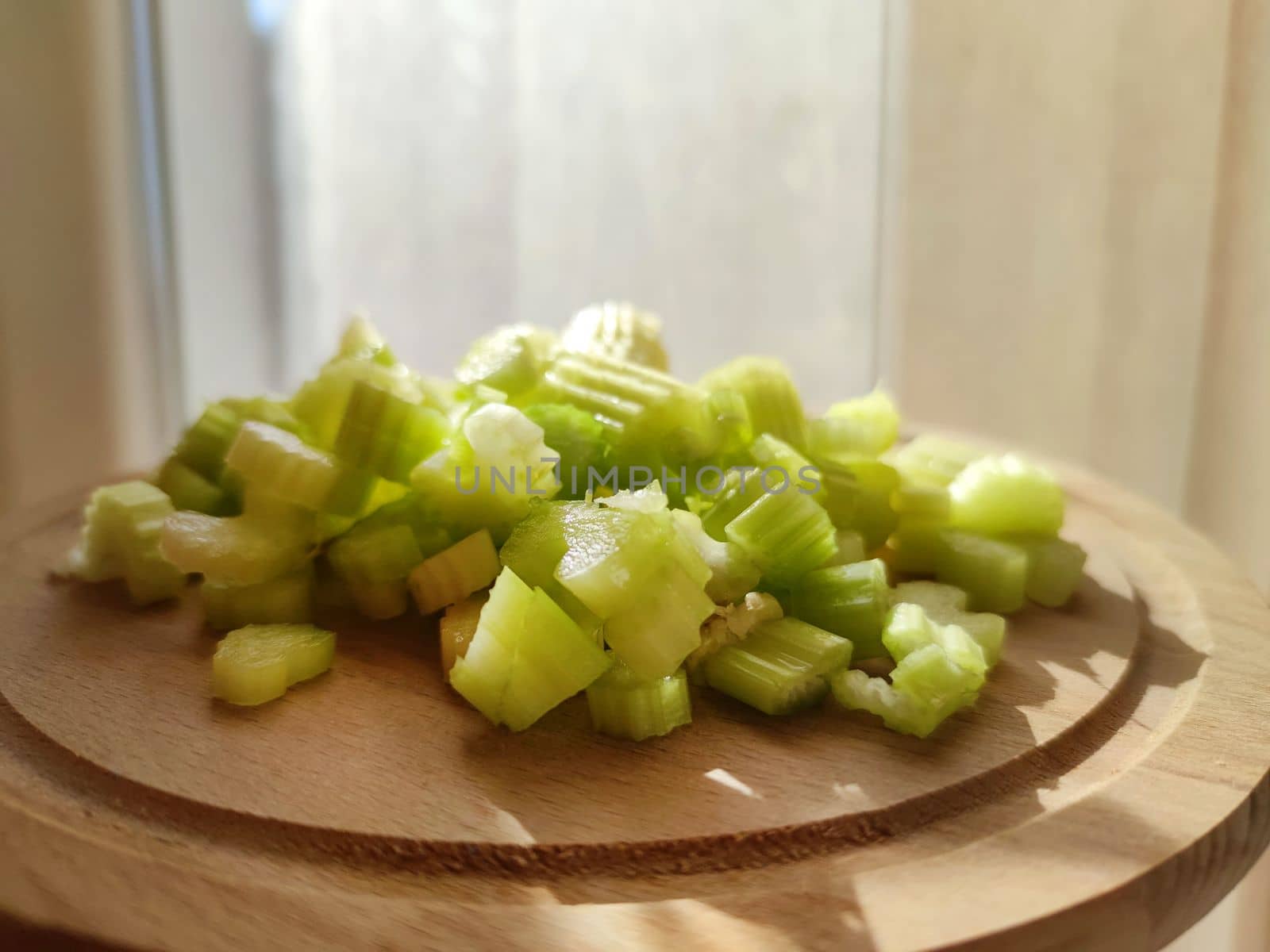 fresh chopped celery stalks on a wooden board in sunlight by Annado