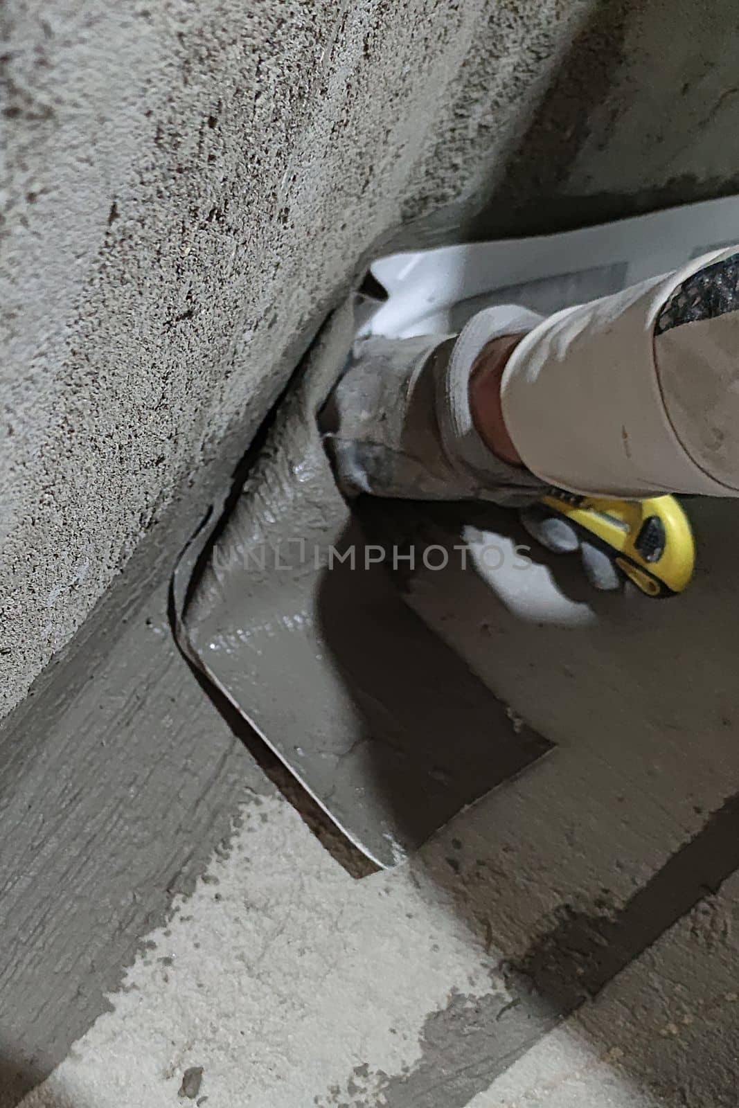 a worker sticking bathroom waterproofing tape on a corner.