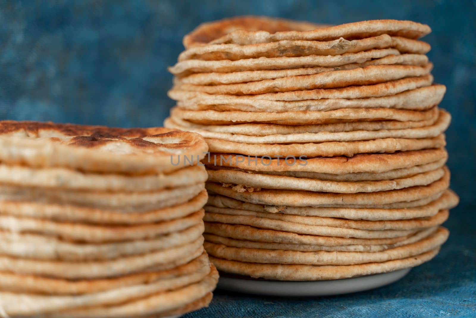 Flatbread lavash, chapati, naan, heap of tortilla on a blue background Homemade flatbread stacked. by Matiunina