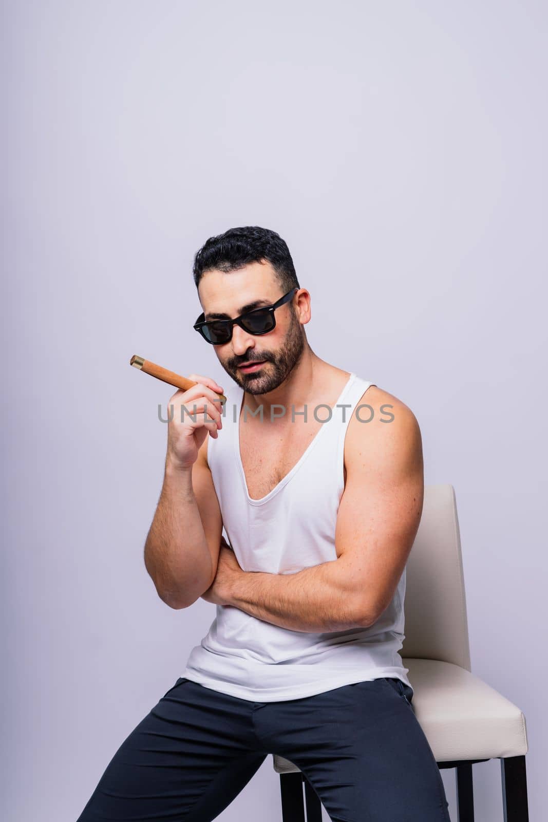 Close-up bearded caucasian man smoking cigar. Wearing white shirt. Studio portrait