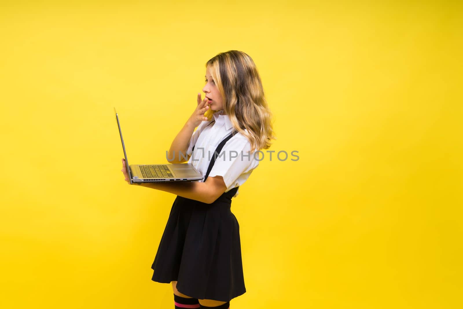 Little happy blonde kid girl 12-13 years laptop pc computer. Children lifestyle childhood concept. by Zelenin
