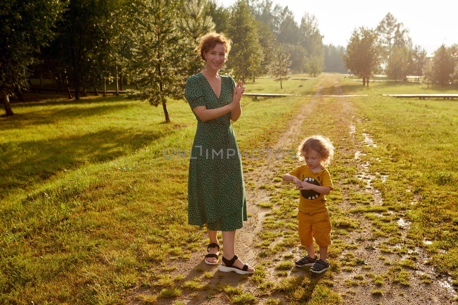 Cheerful mother with son standing on grassy footpath by Demkat
