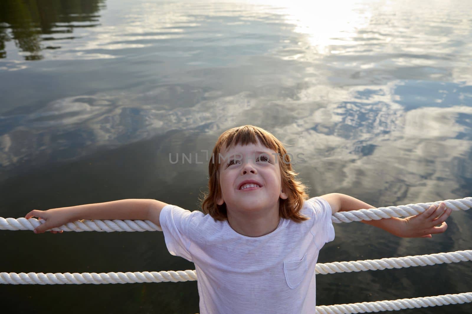 Boy leaning on ropes near lake water by Demkat