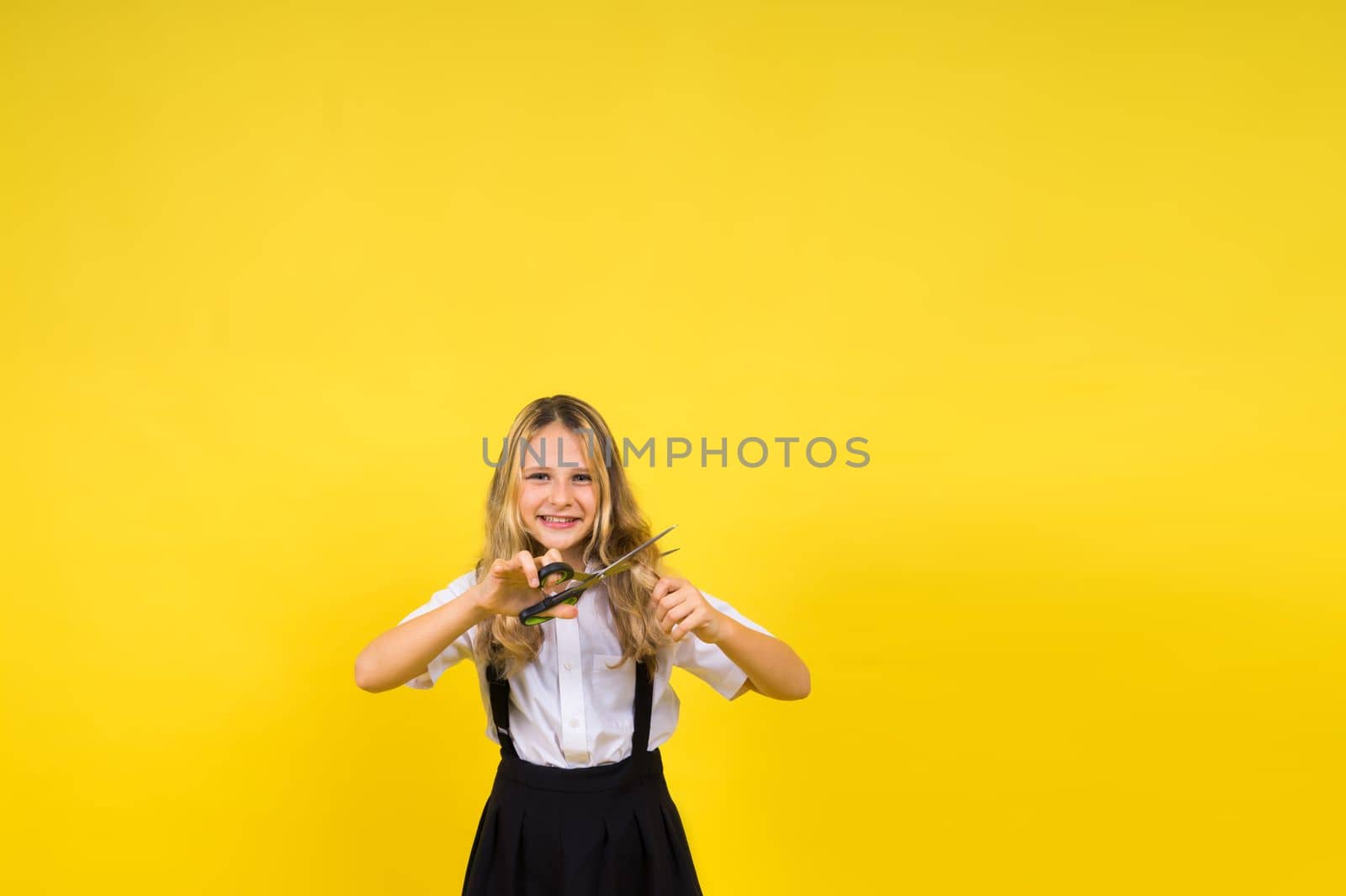 Teenage school girl with scissors, isolated on yellow background. Child creativity, arts and crafts. by Zelenin