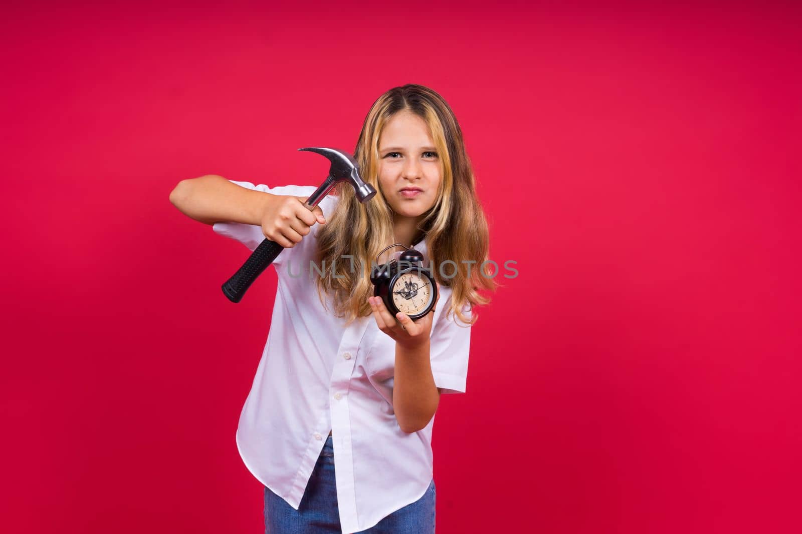 Kid girl holding hammer and alarm clock smiling with happy and cool smile on face. showing teeth.