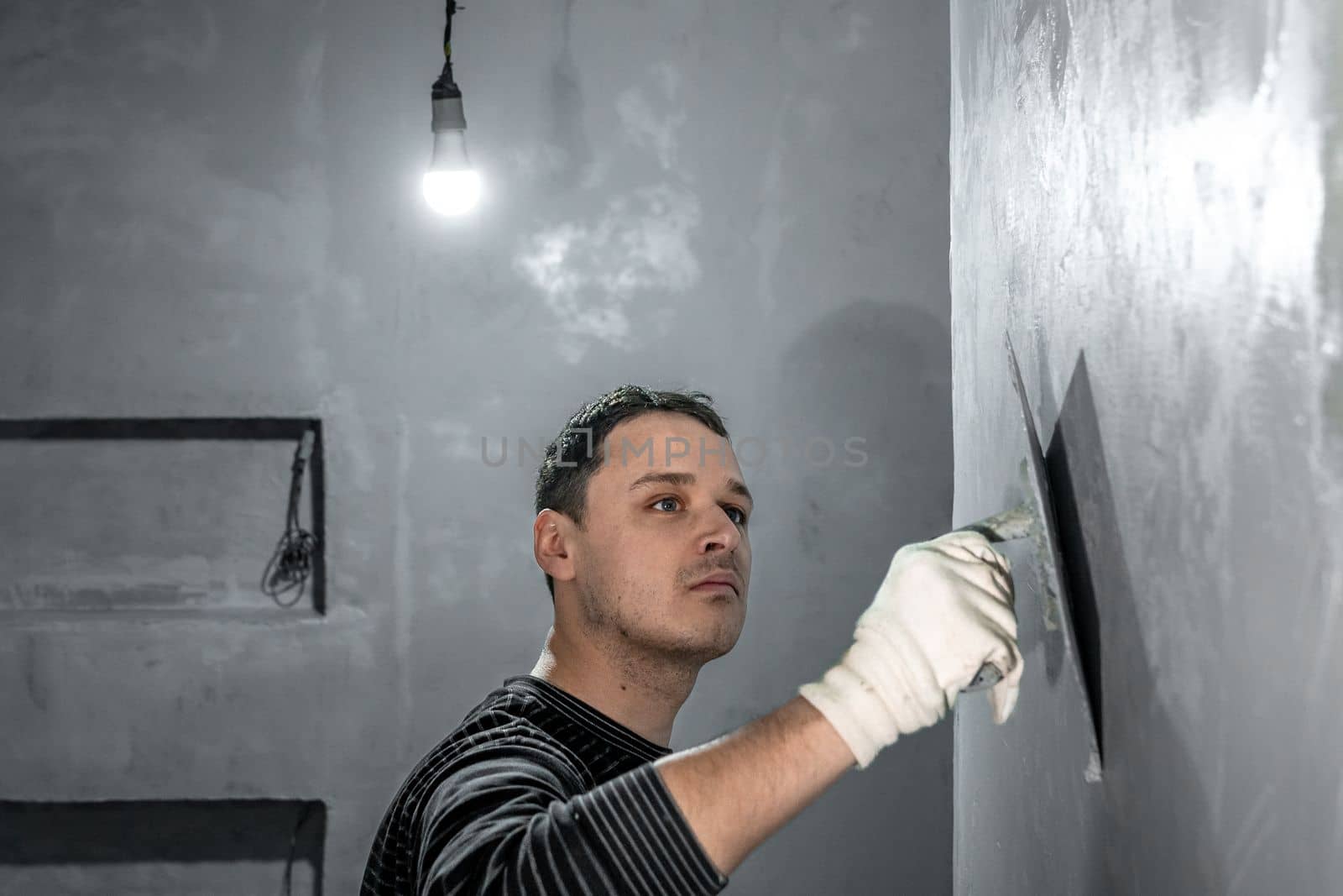 man applies insulation to a bathroom wall by Edophoto