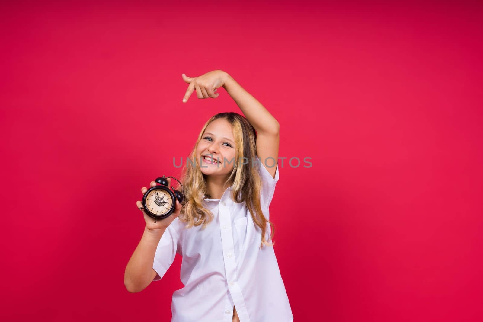 Teen girl 12, 13, 14 years old look at alarm clock. Good morning, checking time. Positive emotions. by Zelenin