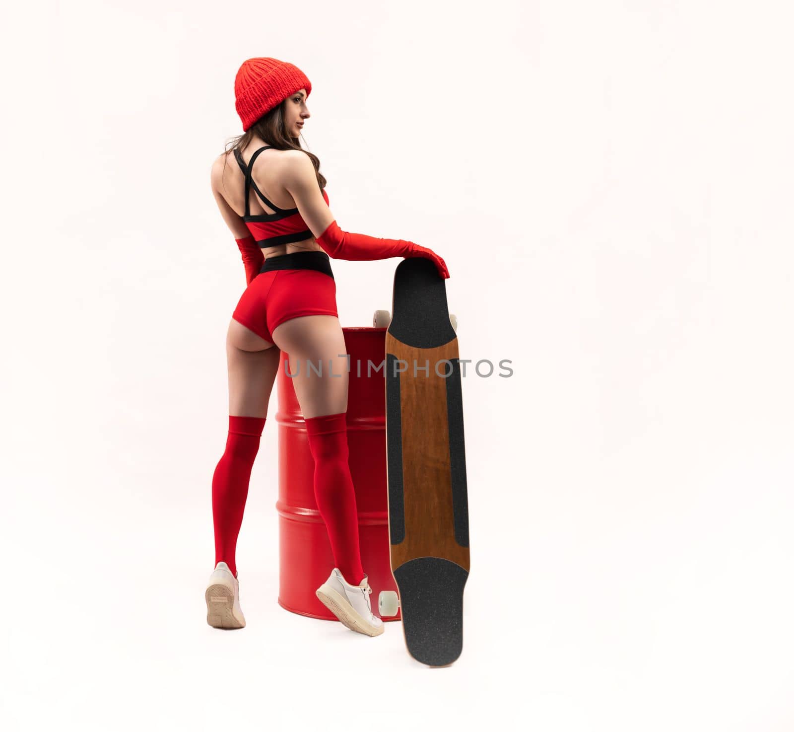 sexy girl in a red hat with a longboard in short red sports summer clothes